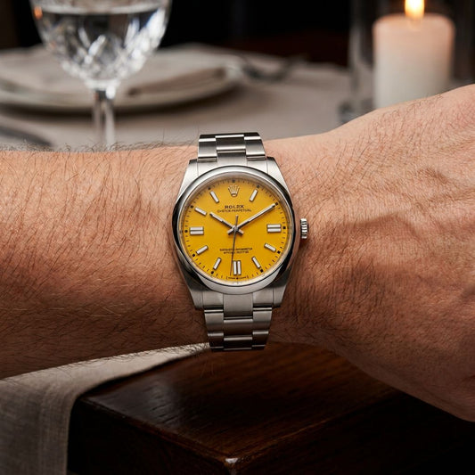 A Rolex Submariner watch with a bright yellow dial and a silver stainless steel bracelet, worn on a person's wrist in a dimly lit, elegant setting with a blurred wine glass and candle in the background.