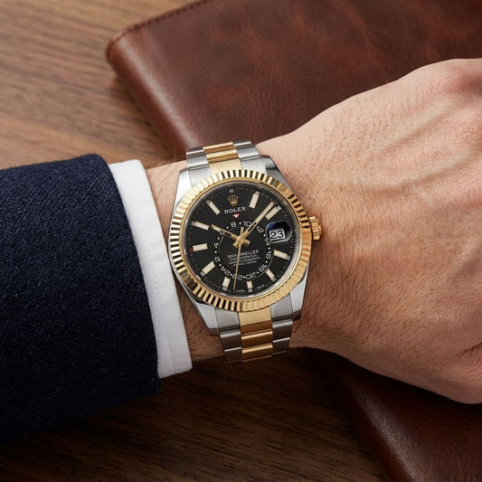 A Rolex Submariner Date watch with a two-tone gold and silver stainless steel bracelet, worn on a wrist. The watch features a black dial with gold-tone indices and a gold fluted bezel.