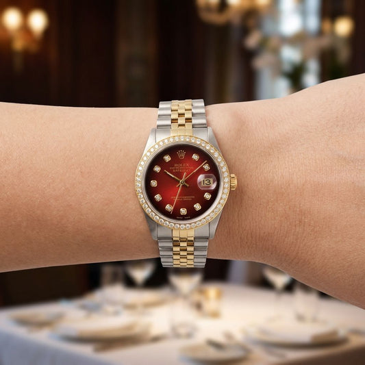 A Rolex watch with a red dial, diamond-set bezel, and two-tone silver and gold Oyster bracelet, shown worn on a person's wrist in a blurred indoor setting.