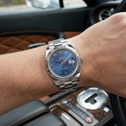 A Rolex Datejust watch with a blue dial and stainless steel Oyster bracelet worn on a person's wrist inside a car.